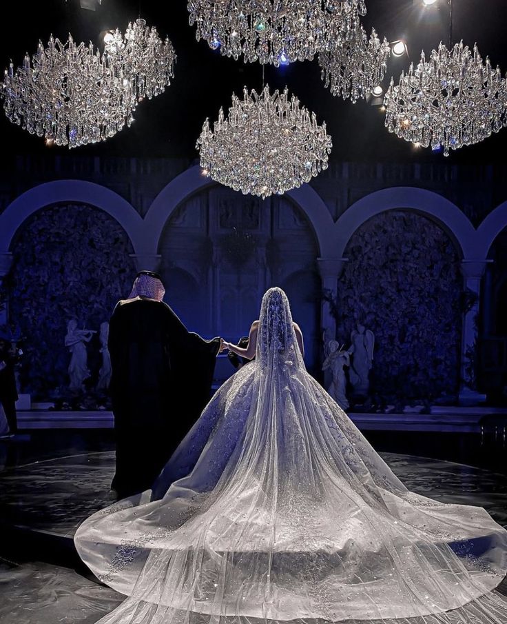 a bride and groom standing in front of chandeliers