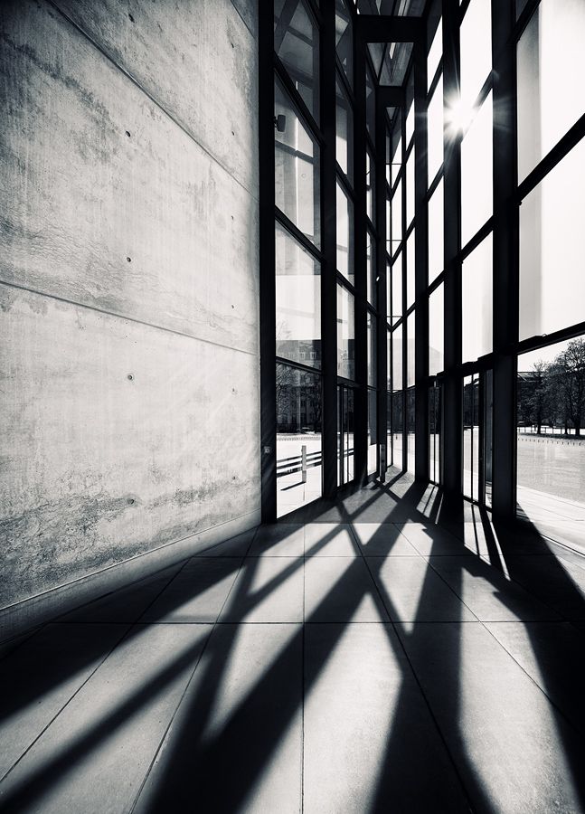 black and white photograph of the inside of a building with long shadows on the wall