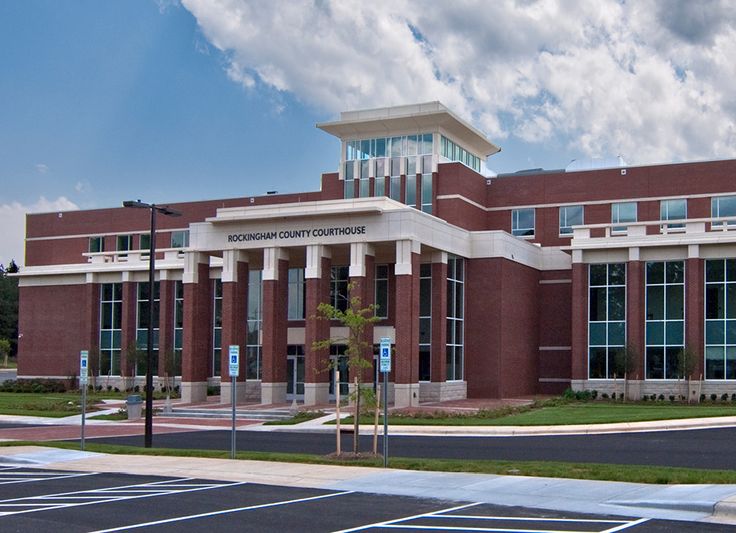 an empty parking lot in front of a large brick building with columns on the side