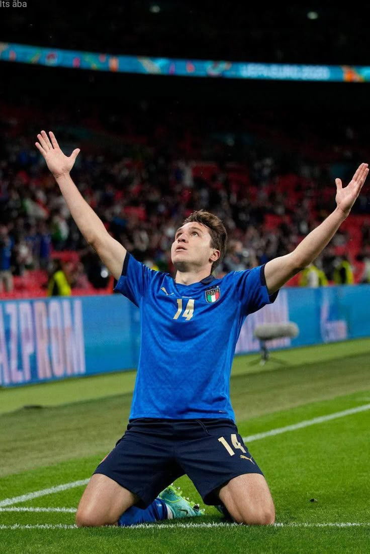 a soccer player sitting on the ground with his arms in the air as he looks up