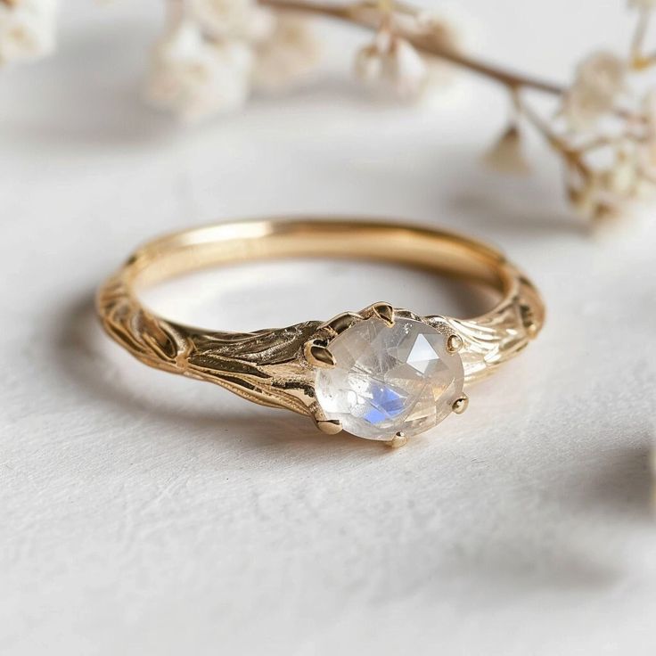 a close up of a ring on a white surface with flowers in the back ground