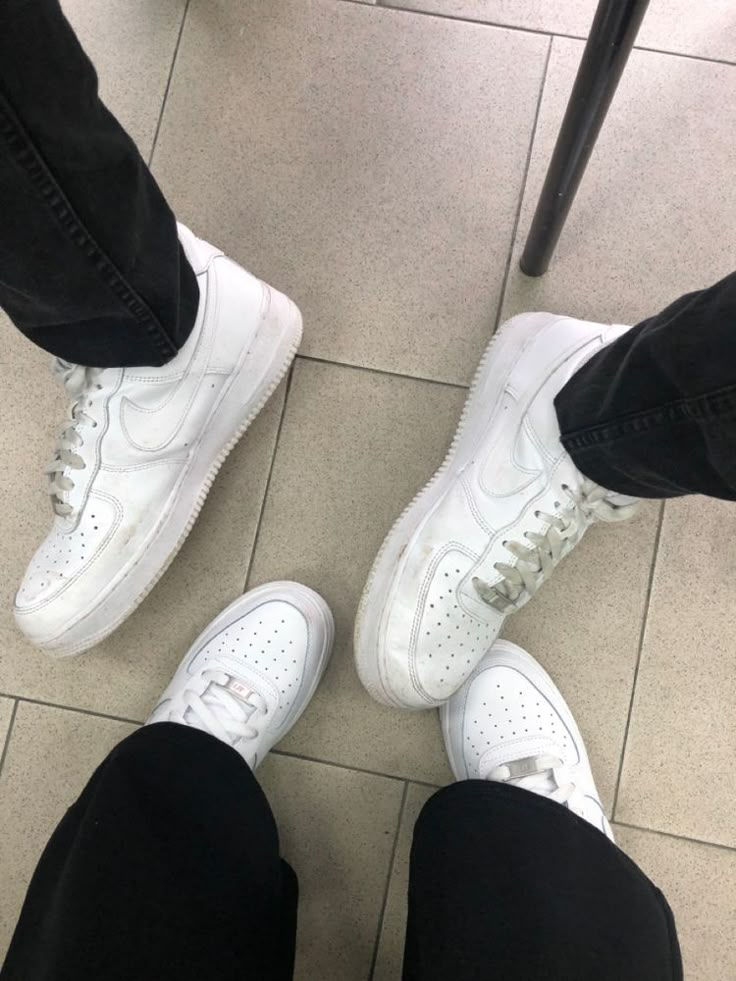 two people standing next to each other wearing white sneakers