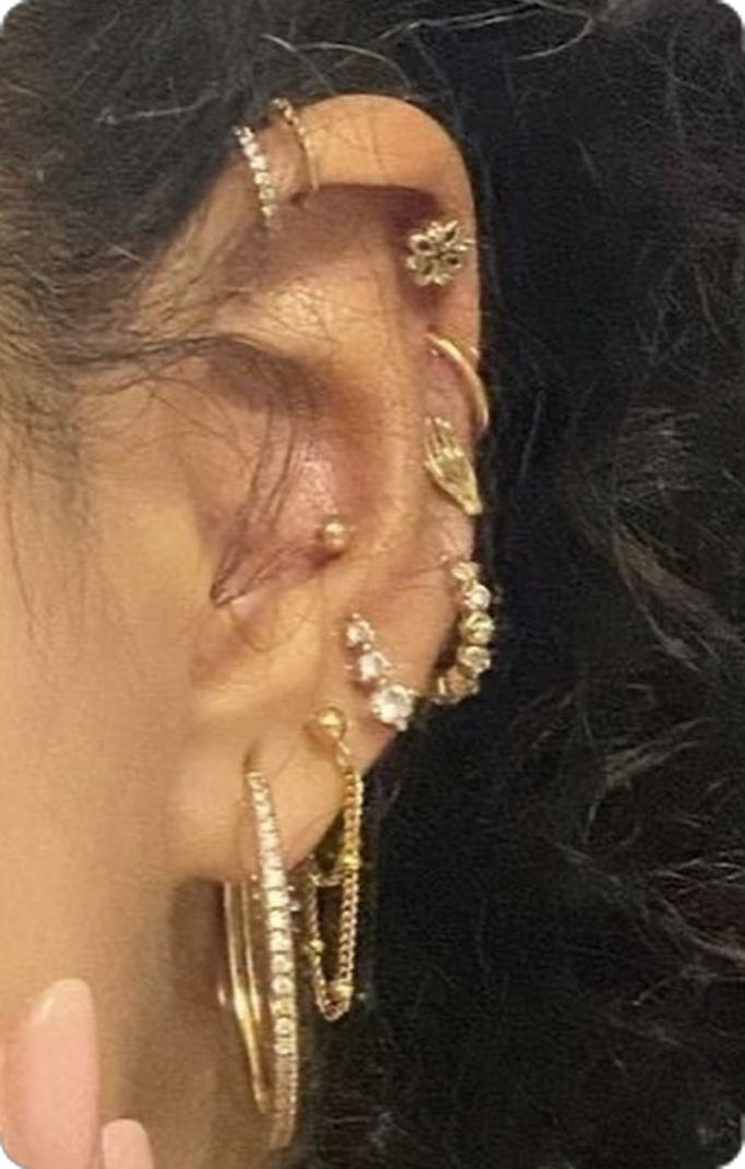 a close up of a person's ear with gold jewelry on top of it