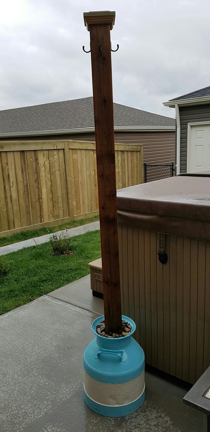 an outdoor hot tub with a wooden pole in the middle and a blue barrel next to it