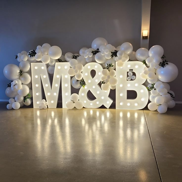 an illuminated sign that says mr and b surrounded by white balloons in the shape of letters