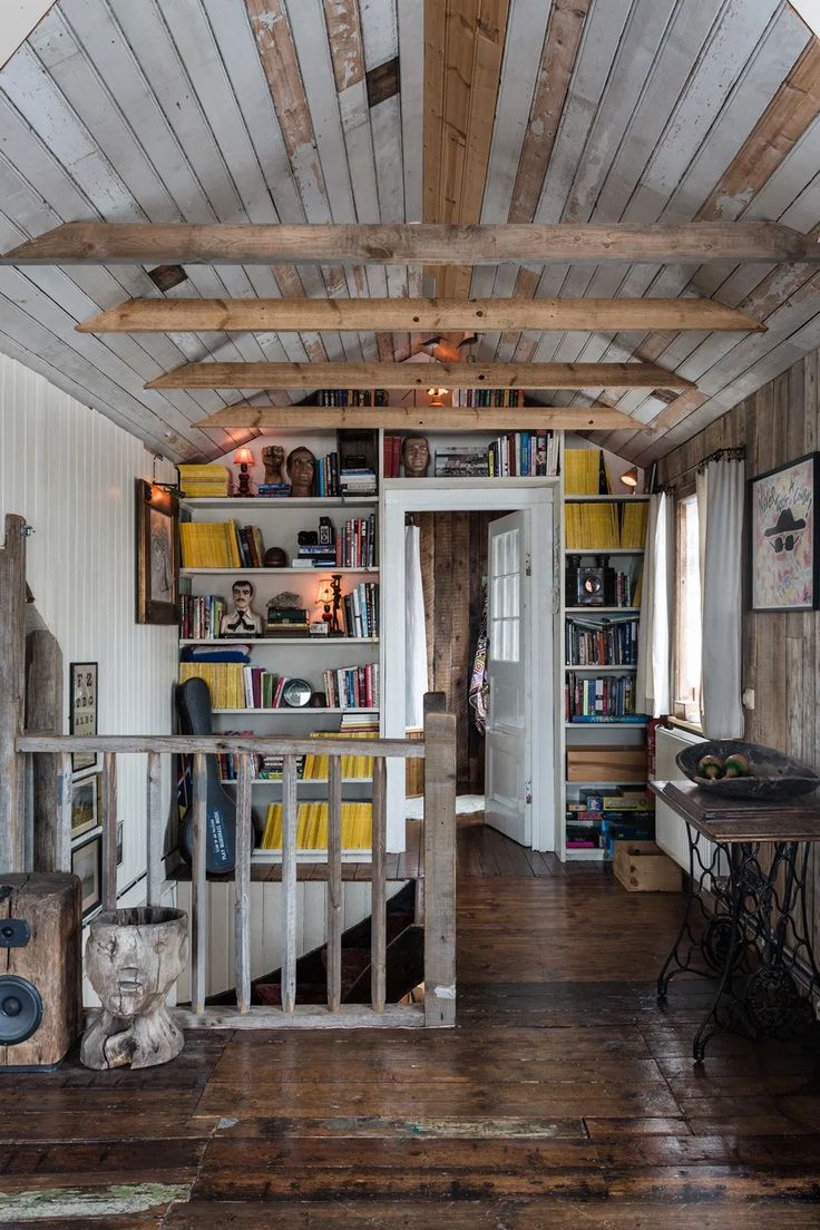 a room with wooden floors and white walls has bookshelves on the wall, an open door leading to another room