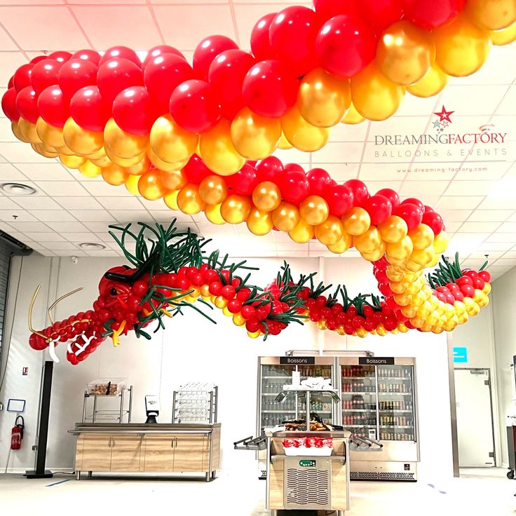 balloons are hanging from the ceiling in an open area with tables and counter tops on either side