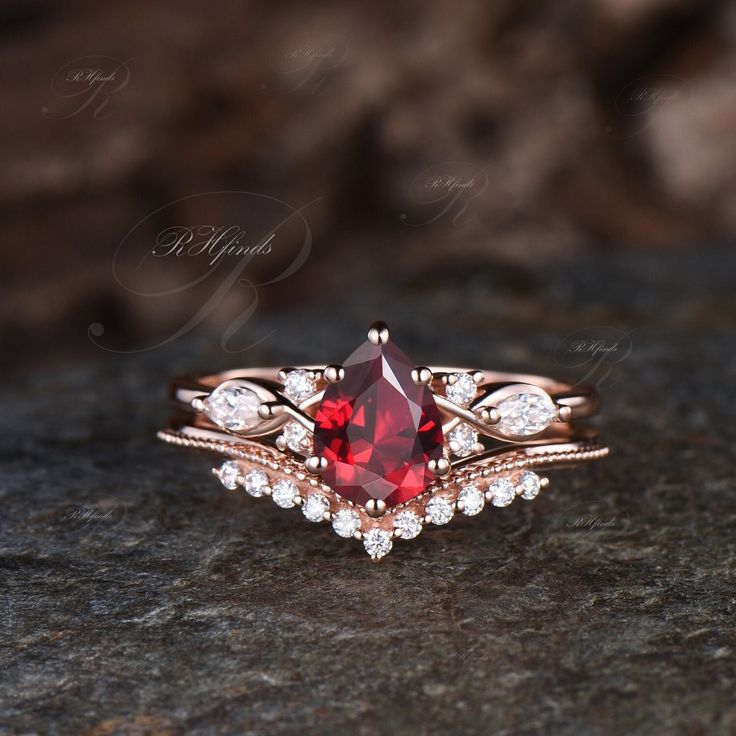 a close up of a ring with a red stone in the middle and diamonds around it