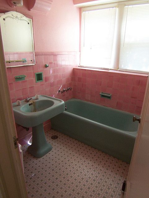 a bathroom with pink tiles and a green bathtub next to a sink in the corner