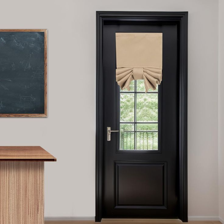 an empty room with a black door and brown window coverings on the windowsill