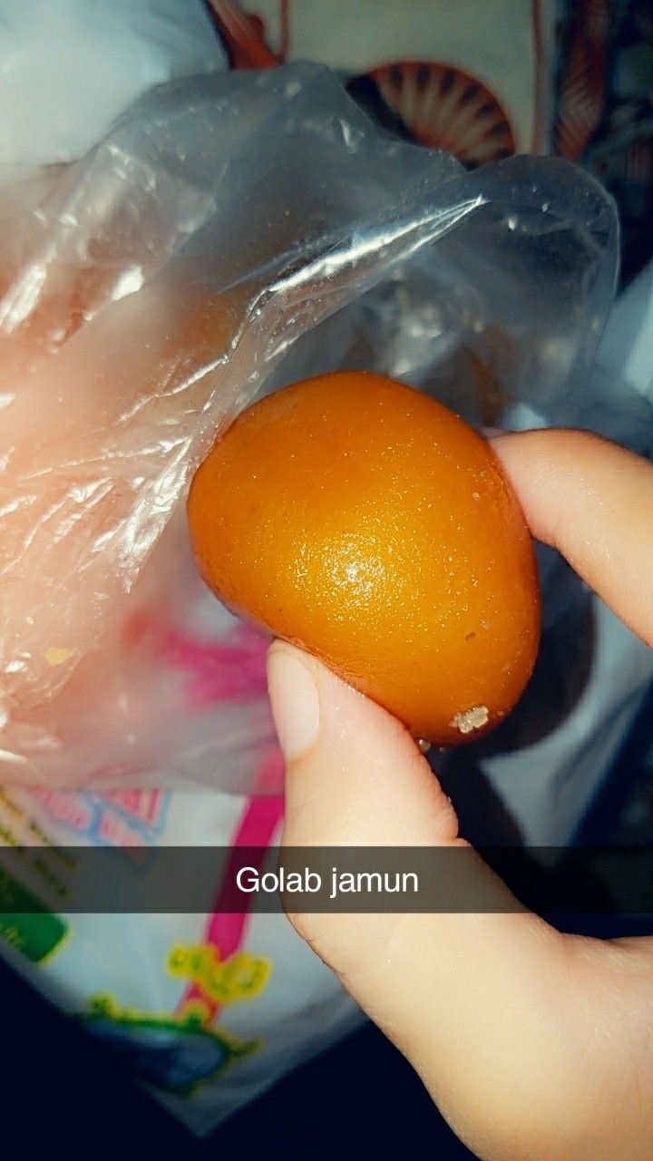 a person holding an orange in their hand with plastic bags on the back of it