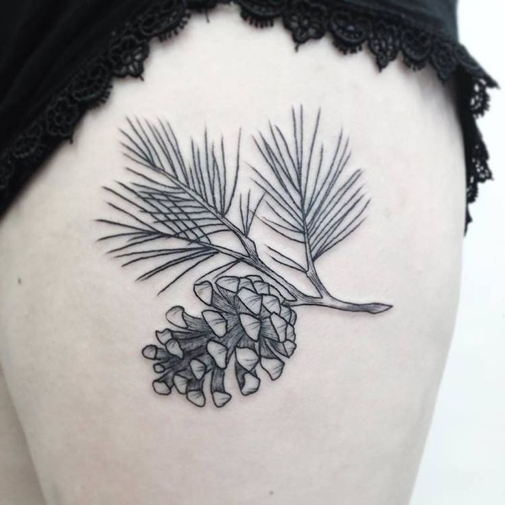 a pine cone tattoo on the back of a woman's thigh, with leaves and cones