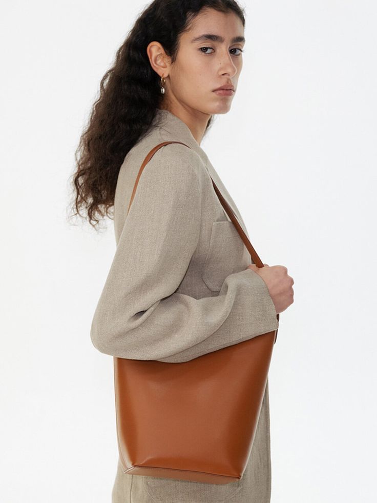 Editor's NotesROWH presents a bucket shopper bag with a timeless design that complements a variety of outfits. - Bucket bag style- Single long top handle- Relaxed silhouette- Inner card slots- Spacious storage- Classic and casual style Measurements(in.)One Size- Size: 10.24 in. (W) * 10.83 in. (H) * 4.72 in. (D)- Strap: 10.24 in. (L) Composition & Care- Material: Shell: 100% Cow Leather, 100% Cotton / Lining: 65% Polyester, 35% Cotton / Strap: 100% Cow Leather- Natural leather may have fine scratches and wrinkles- Bright leather can get stained by denim or dark outfits- Avoid direct heat and moisture- Wipe off moisture and stains with a dry cloth- Natural dry in the shade- Avoid friction to prevent the peel-off from the metal plating- Be cautious when using wet Chic Bucket-shape Shoulder Bag For Work, Workwear Bucket Hobo Bag With Detachable Handle, Chic Bucket Bag For Work, Chic Bucket Bag For Workwear, Classic Brown Bucket Bag With Top Handle, Modern Cognac Shoulder Bucket Bag, Cognac Bucket Bag With Handle Drop, Classic Bucket Hobo Bag With Detachable Handle, Classic Cognac Hobo Bag For Shopping