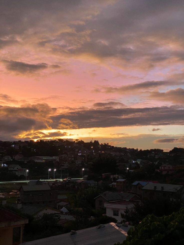 the sun is setting over some houses and trees