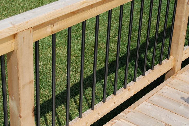 a wooden bench sitting on top of a grass covered field next to a metal railing