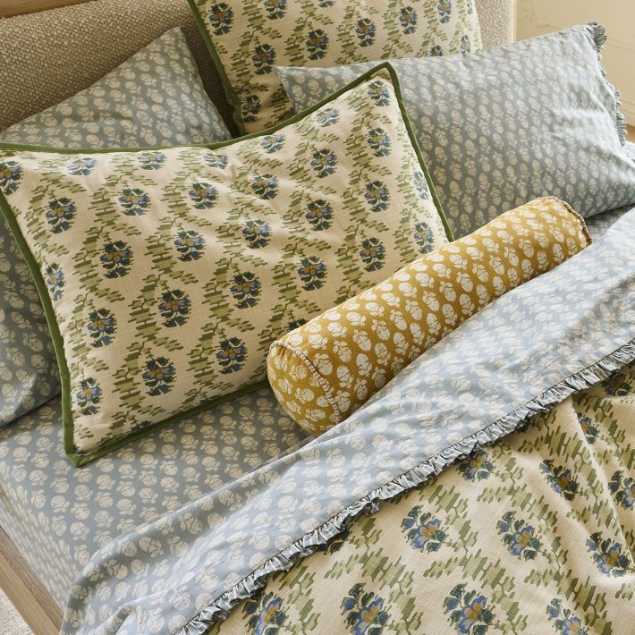 a bed with blue and green pillows on it's headboard next to a pillow