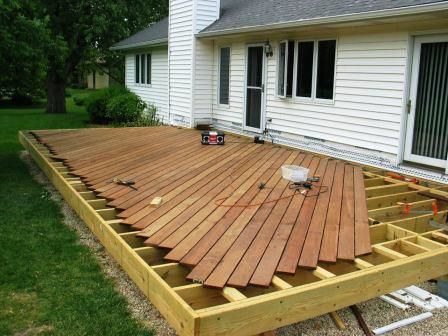 a wooden deck is being built in front of a white house with siding on it