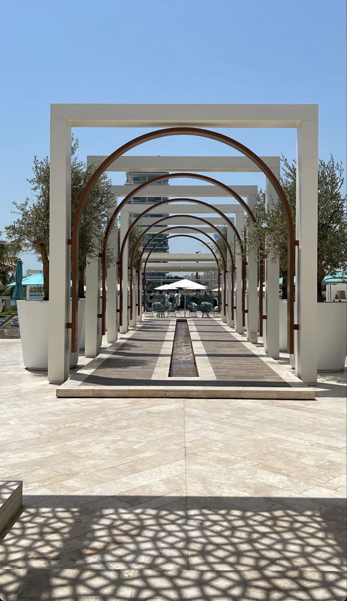 the walkway is lined with white pillars and umbrellas