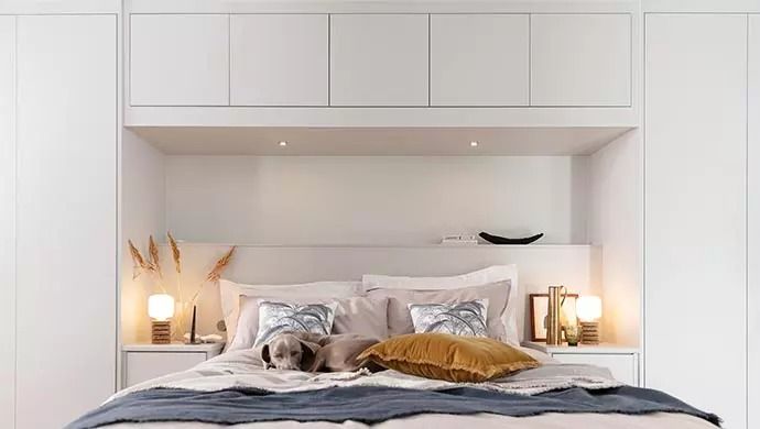 the bed is made with white linens and pillows, along with two lamps on either side