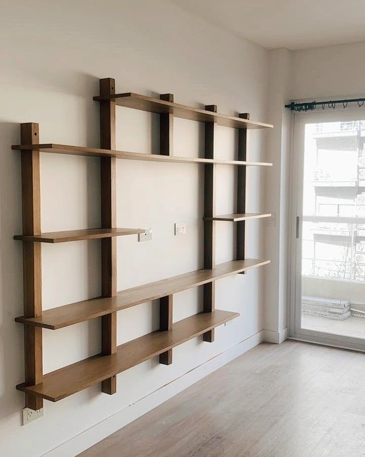 an empty room with wooden shelves on the wall and a sliding glass door in the background