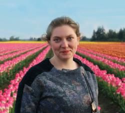 a woman standing in front of a field full of pink and yellow tulips