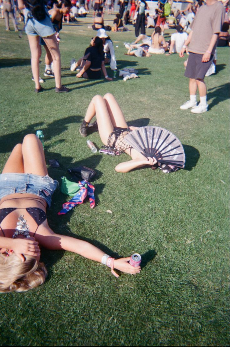 two women laying on the grass with fans