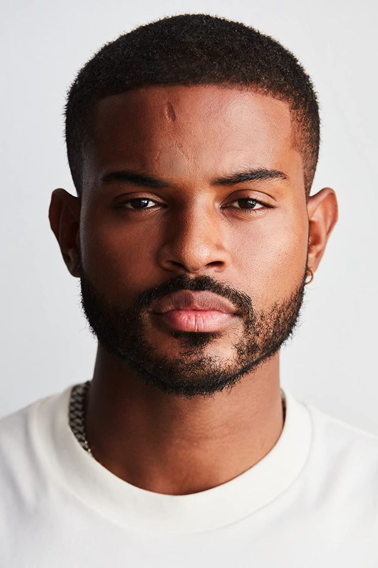 a close up of a person wearing a white t - shirt with a beard and necklace