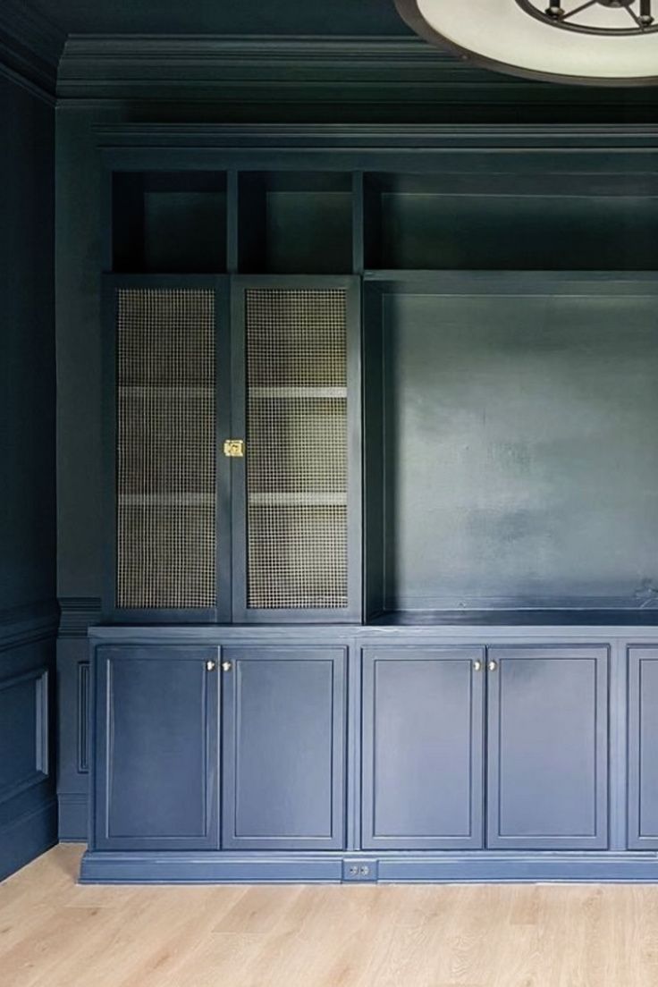 an empty room with blue painted cabinets and wood flooring on the walls, along with a round light fixture