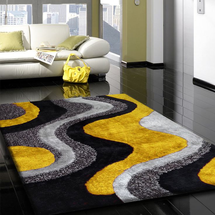 a black and yellow rug in a living room next to a white couch with pillows on it