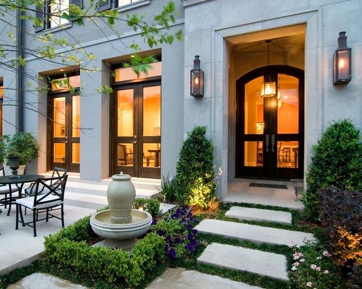 an outdoor dining area in front of a house with stone steps leading up to it