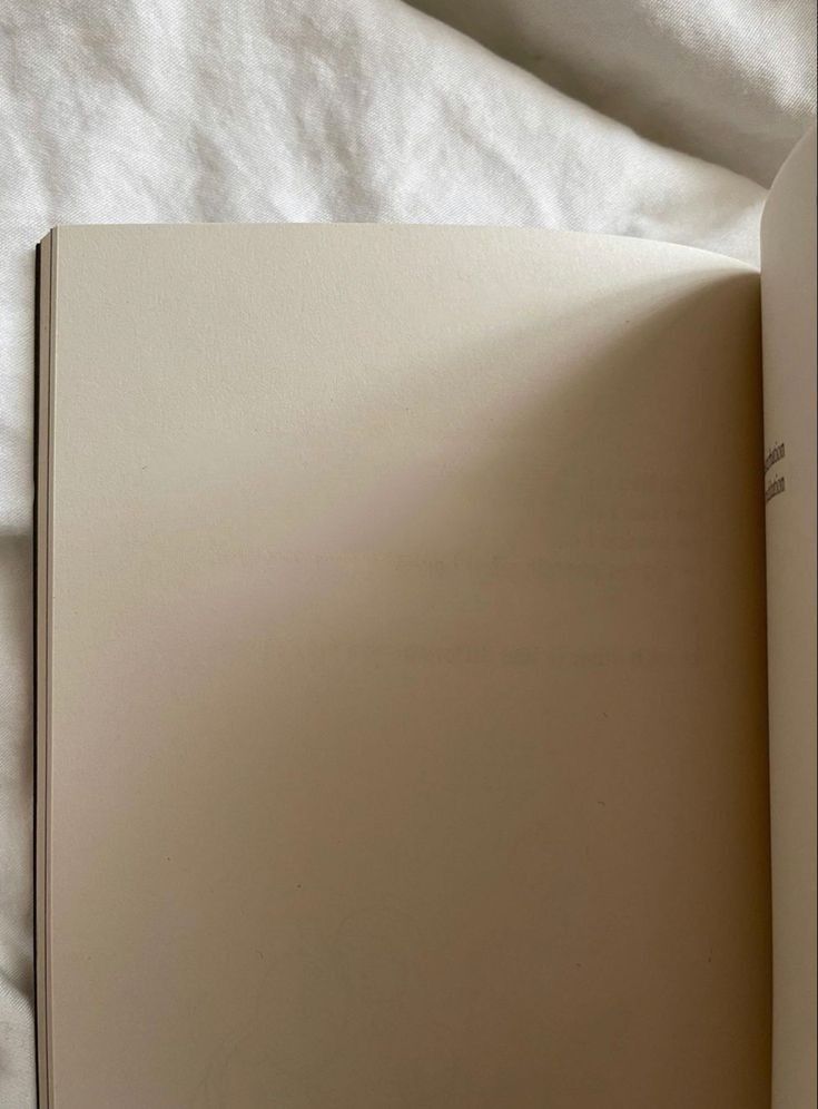 an open book sitting on top of a bed next to a white sheet covered floor