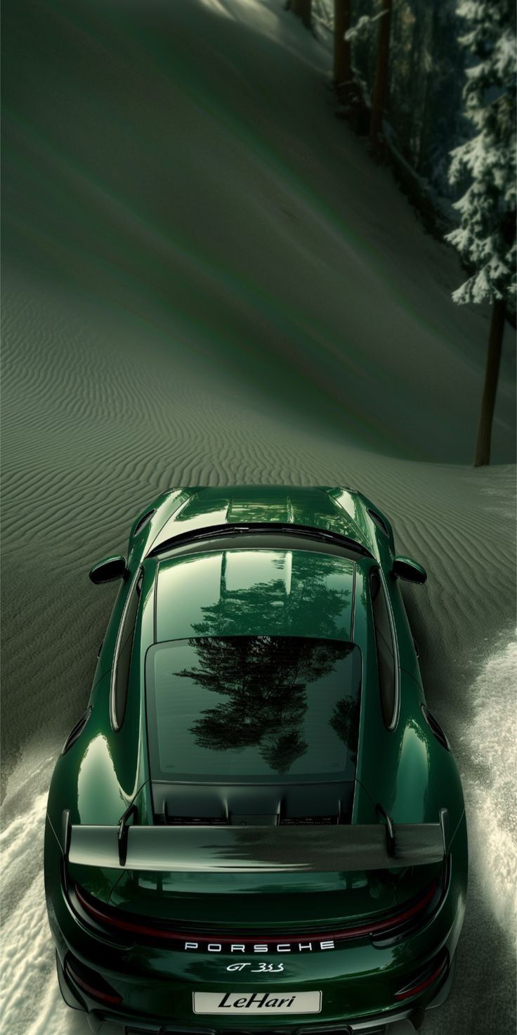 a green sports car parked in the middle of a snow covered field with pine trees