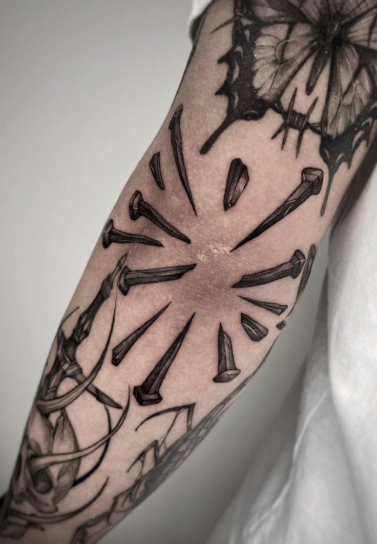 a black and white photo of a clock tattoo on the left upper half of the arm