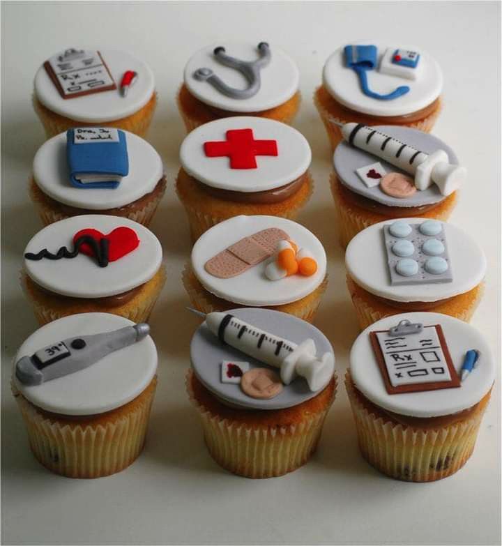 cupcakes decorated with medical related items are arranged on a white table top,