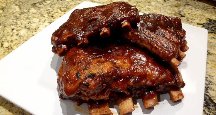 ribs covered in bbq sauce on a white plate