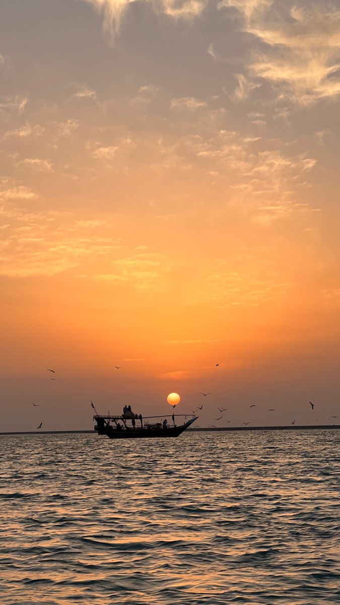 a fishing boat in the ocean at sunset