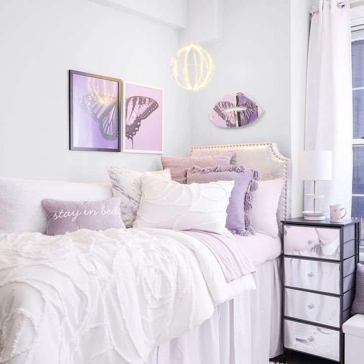 a bed with white sheets and purple pillows