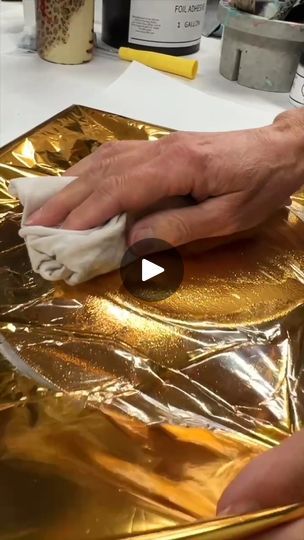 a person wiping gold foil on a table