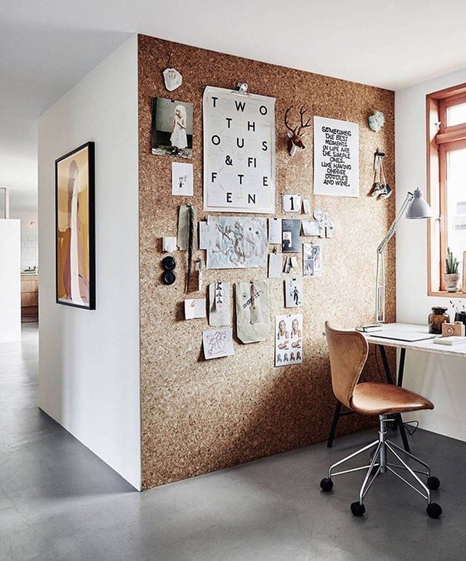 a room with a desk, chair and bulletin board on the wall next to it