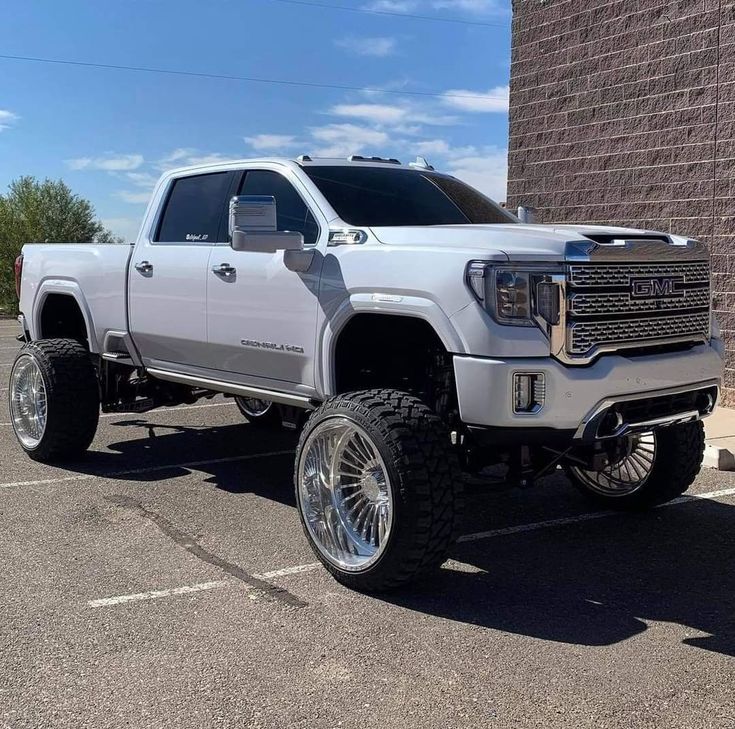 a large white truck parked in a parking lot next to a brick wall and building