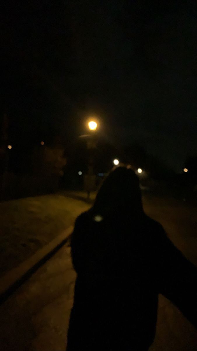 a person is walking down the street at night with their hand in the air and lights on