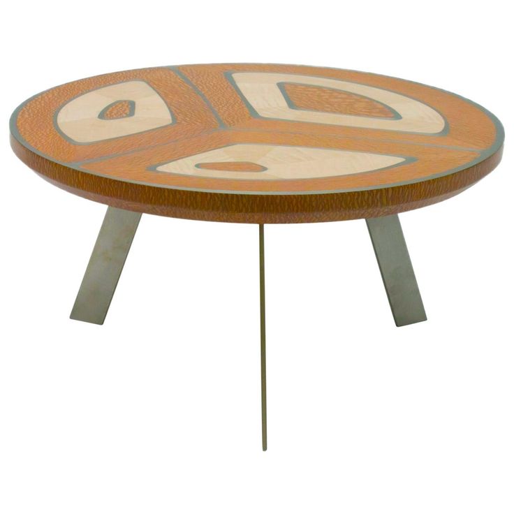 a wooden table with metal legs and an abstract design on the top, sitting against a white background