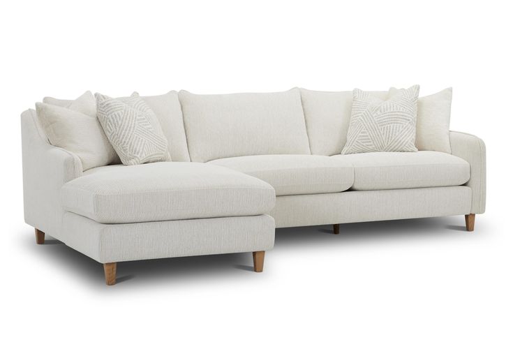 a white sectional couch with pillows on it's back and side facing each other