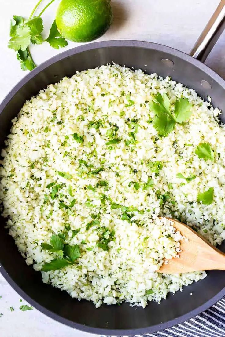 a pan filled with rice and cilantro on top of a counter next to limes