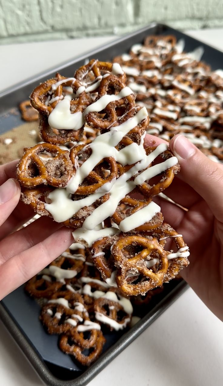 a person is holding up some pretzels with white icing on them and drizzled