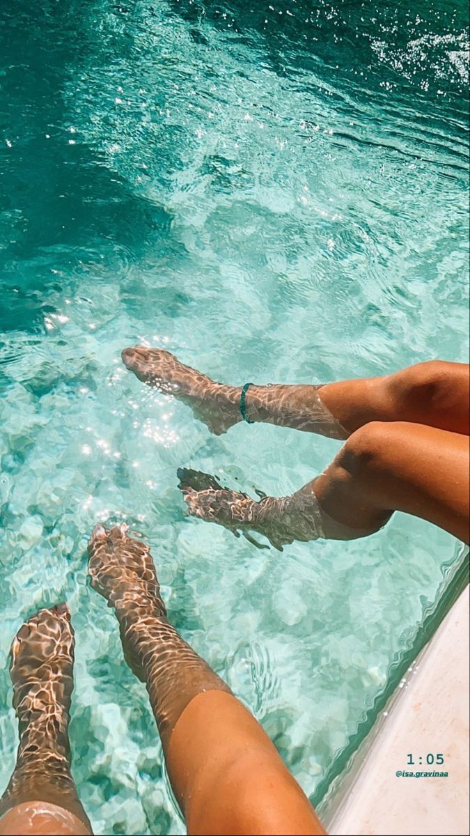 two people are sitting in the water with their feet up