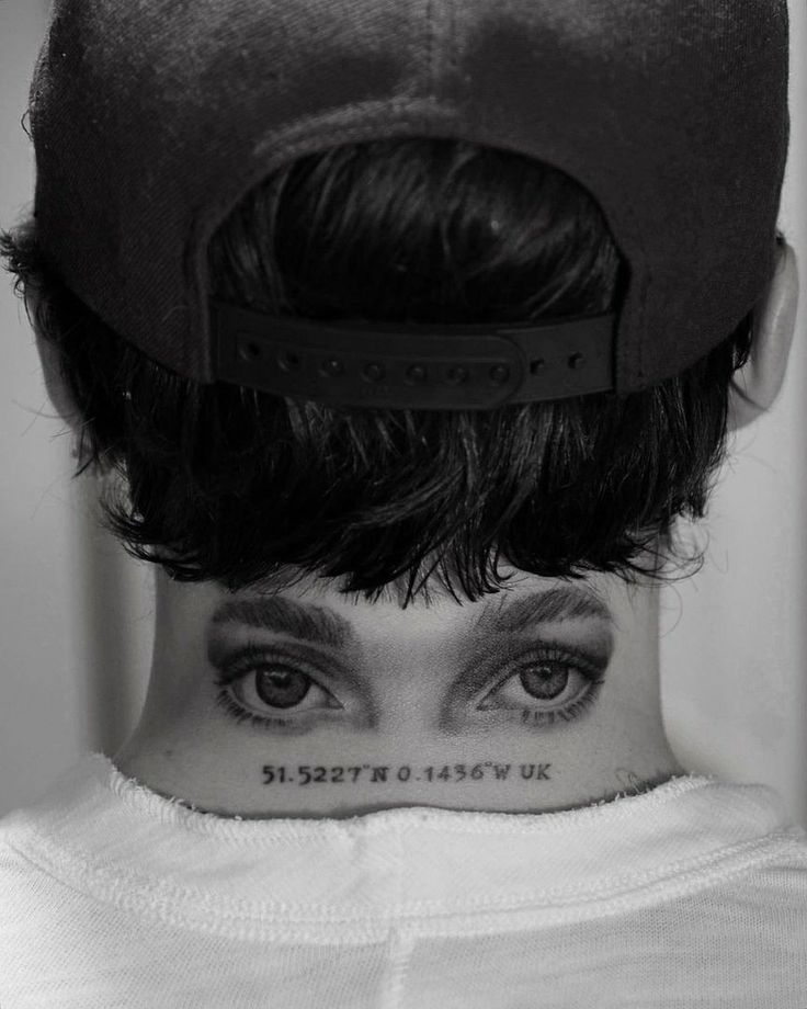 a woman with tattoos on her neck and eyes is looking at the camera while wearing a hat