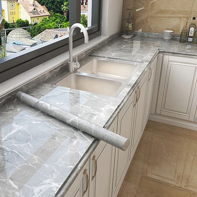 a kitchen with marble counter tops and white cabinets in front of a window overlooking the city