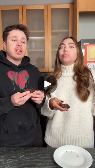 two people standing in front of a table with food on it and one person holding a piece of cake