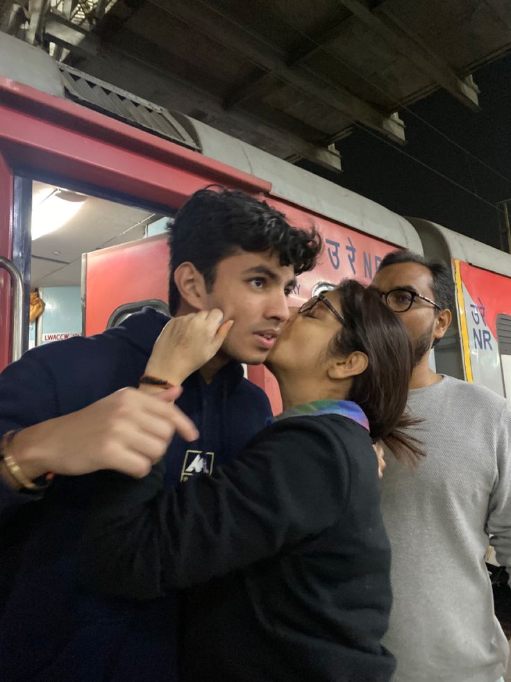 two people standing next to each other in front of a train